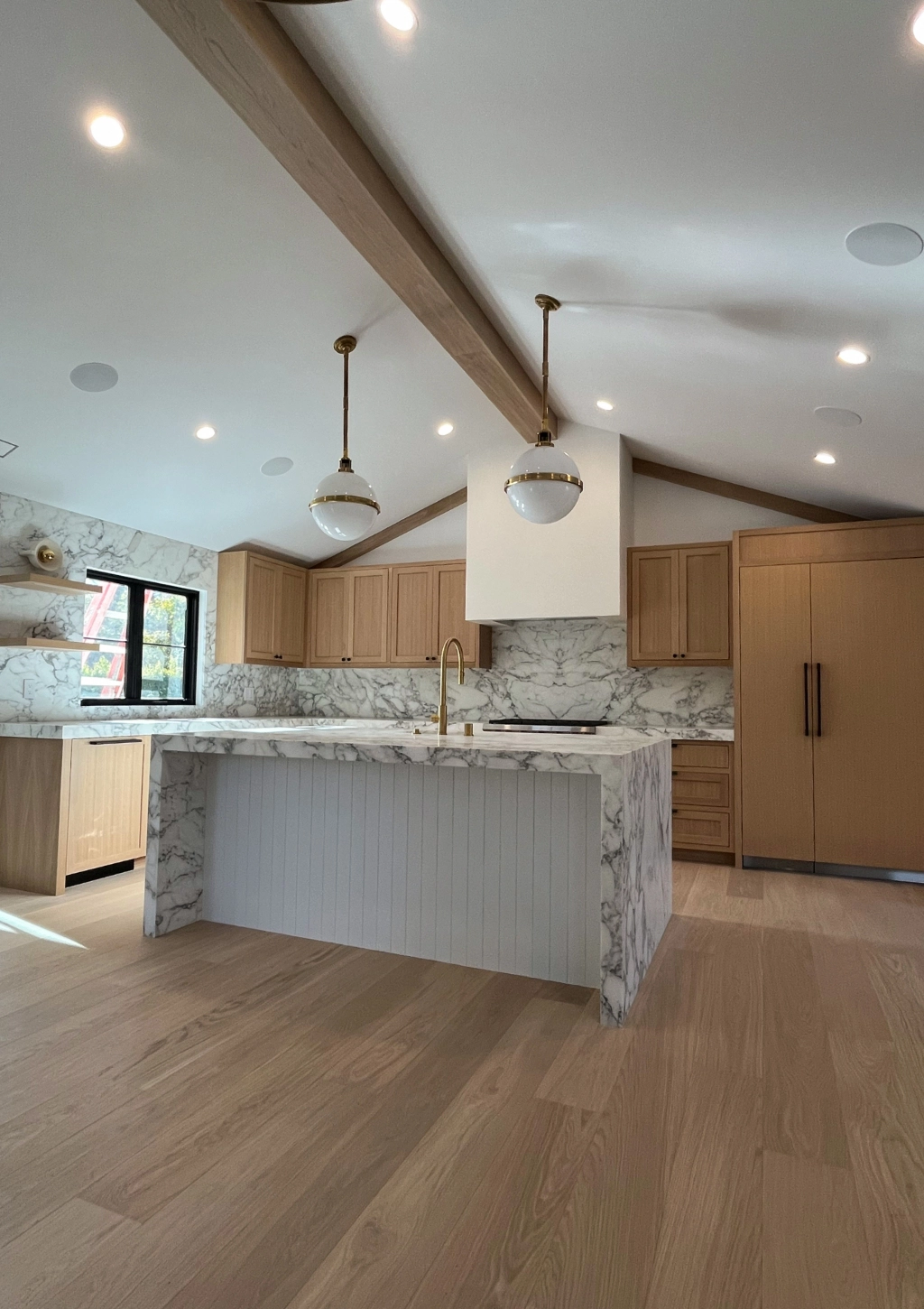 A high-end kitchen remodel with wooden floors and marble countertops.