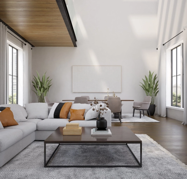 A modern living room with a white sofa, wooden coffee table, and potted plants. In the background, a dining table with beige chairs is visible. White walls and large windows contribute to a bright atmosphere, showcasing recent home remodeling efforts.