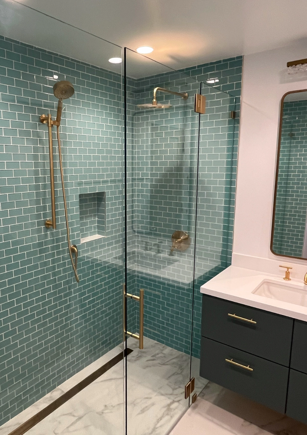 A modern bathroom remodel with blue shower tiles.