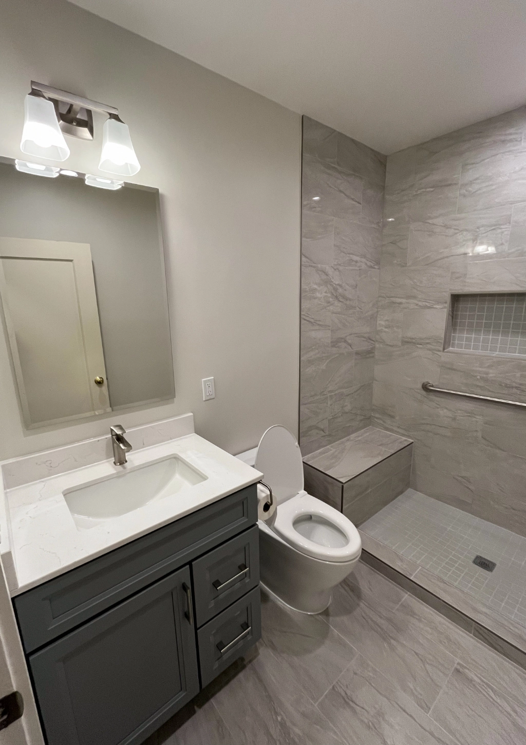 A luxury bathroom with gray shower tiles and new vanity.