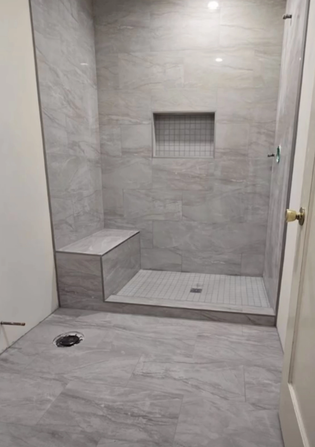 A luxury shower with gray tiles.